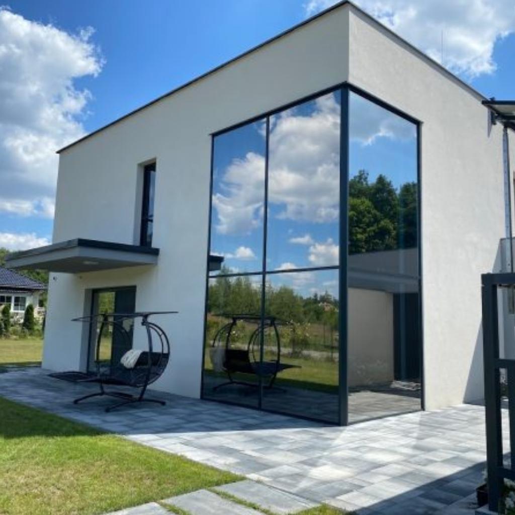 Folia przeciwsłoneczna na dużych oknach domu jednorodzinnego ograniczająca nagrzewanie wnętrz
